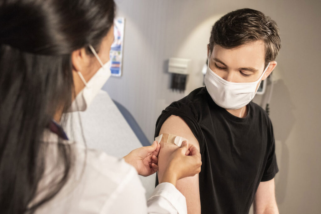 Enfermera colocando un apósito en el brazo de un paciente después de una vacunación.