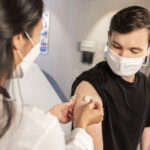 Enfermera colocando un apósito en el brazo de un paciente después de una vacunación.