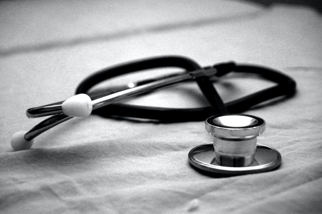 Estetoscopio médico apoyado sobre una sábana o superficie de tela en blanco y negro.