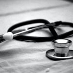 Estetoscopio médico apoyado sobre una sábana o superficie de tela en blanco y negro.